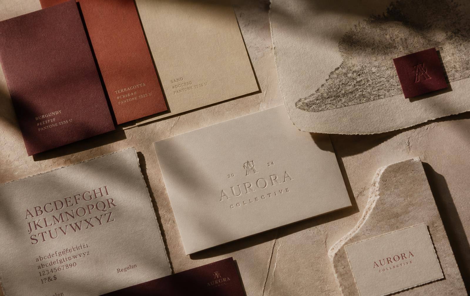 Campioni di carta bordeaux, terracotta e sabbia con caratteri tipografici su superficie in calce crema