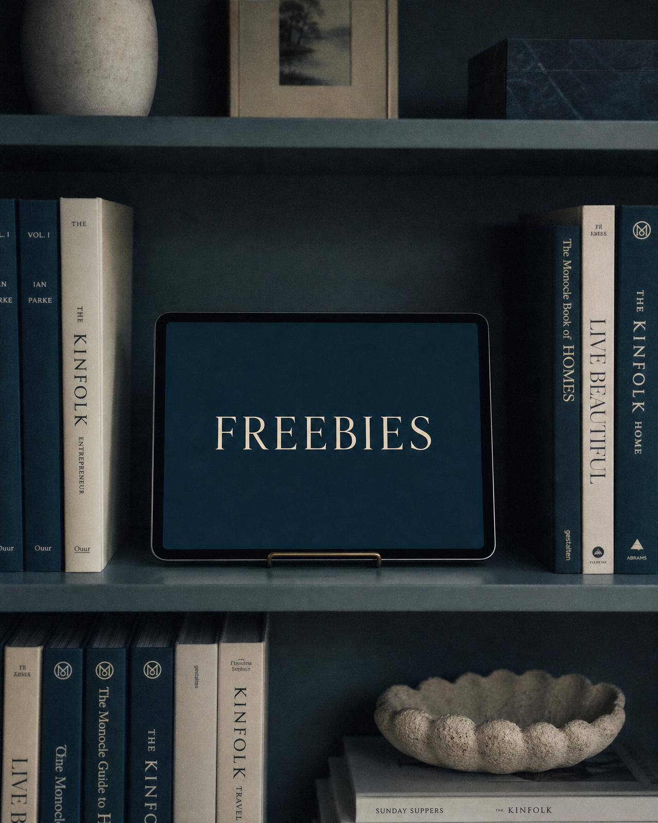 Interno di una libreria curata con libri nei toni petrolio e un tablet con la scritta Freebies