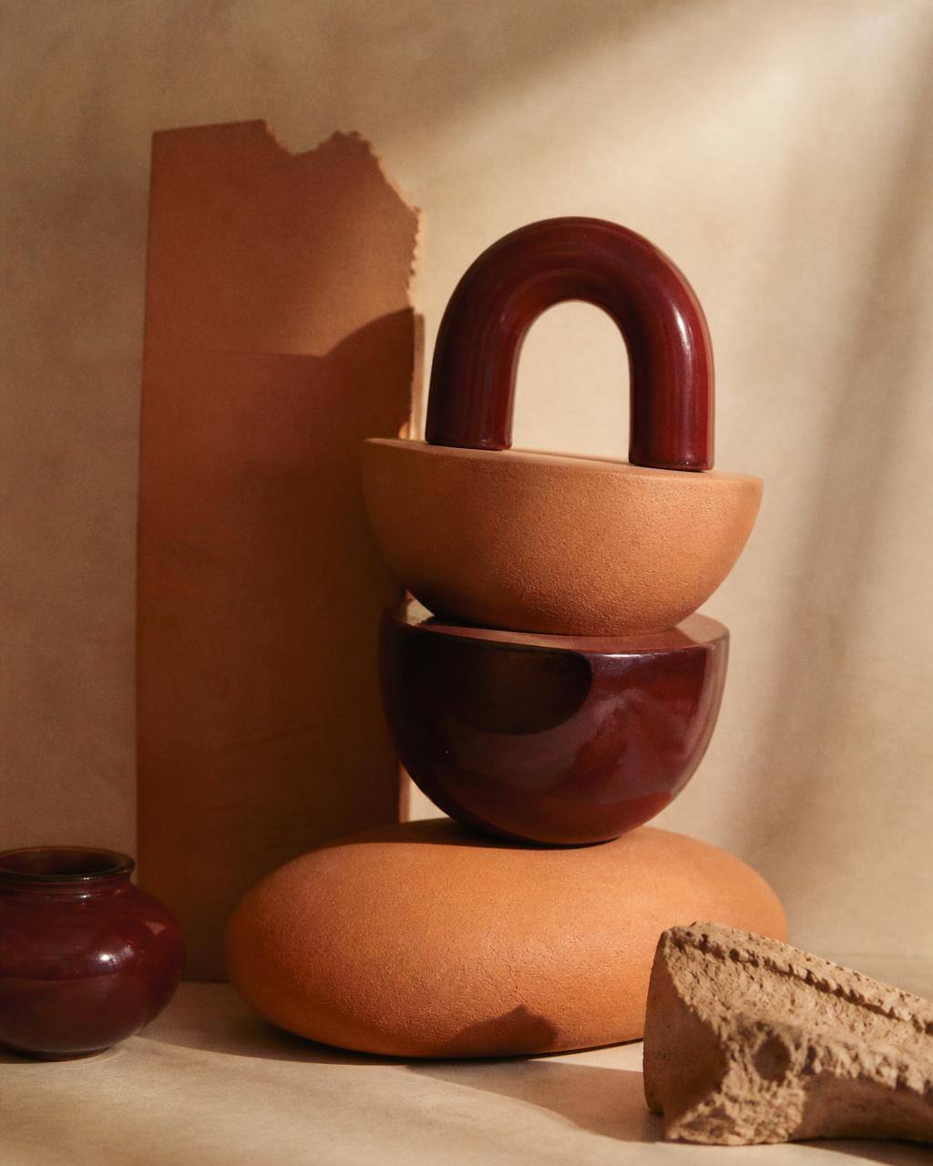 Composizione scultorea di forme in terracotta e ceramica smaltata bordeaux